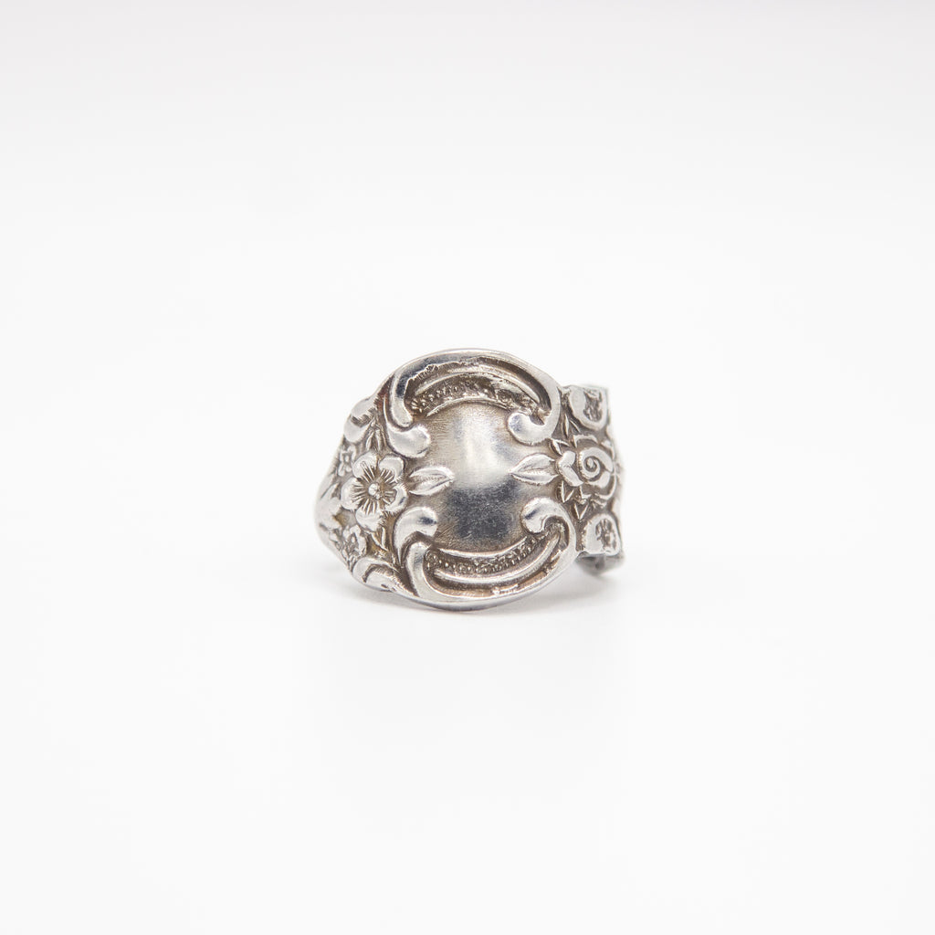 Silver ring with intricate design on a white background