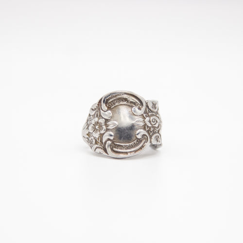 Silver ring with intricate design on a white background